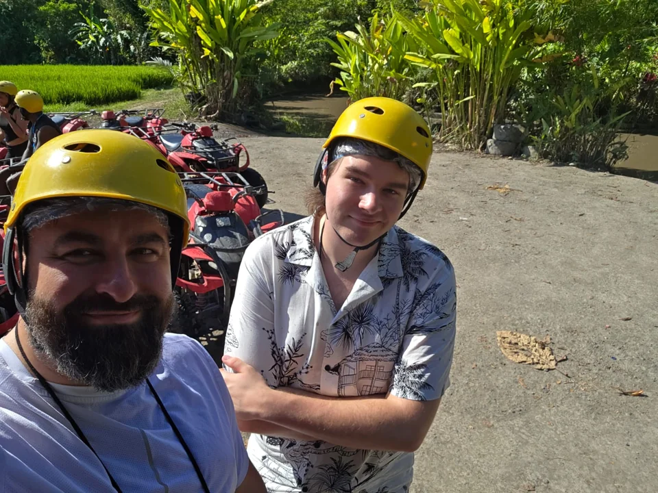 Due viaggiatori con il casco, con veicoli fuoristrada sullo sfondo